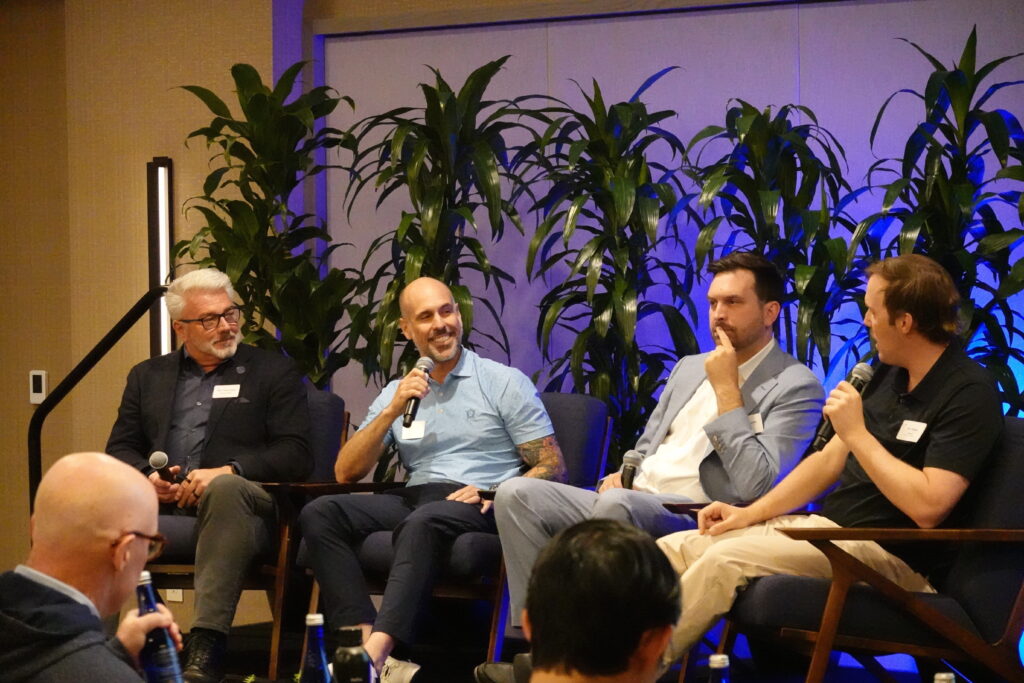 Four panelists sit onstage with microphones during a discussion.