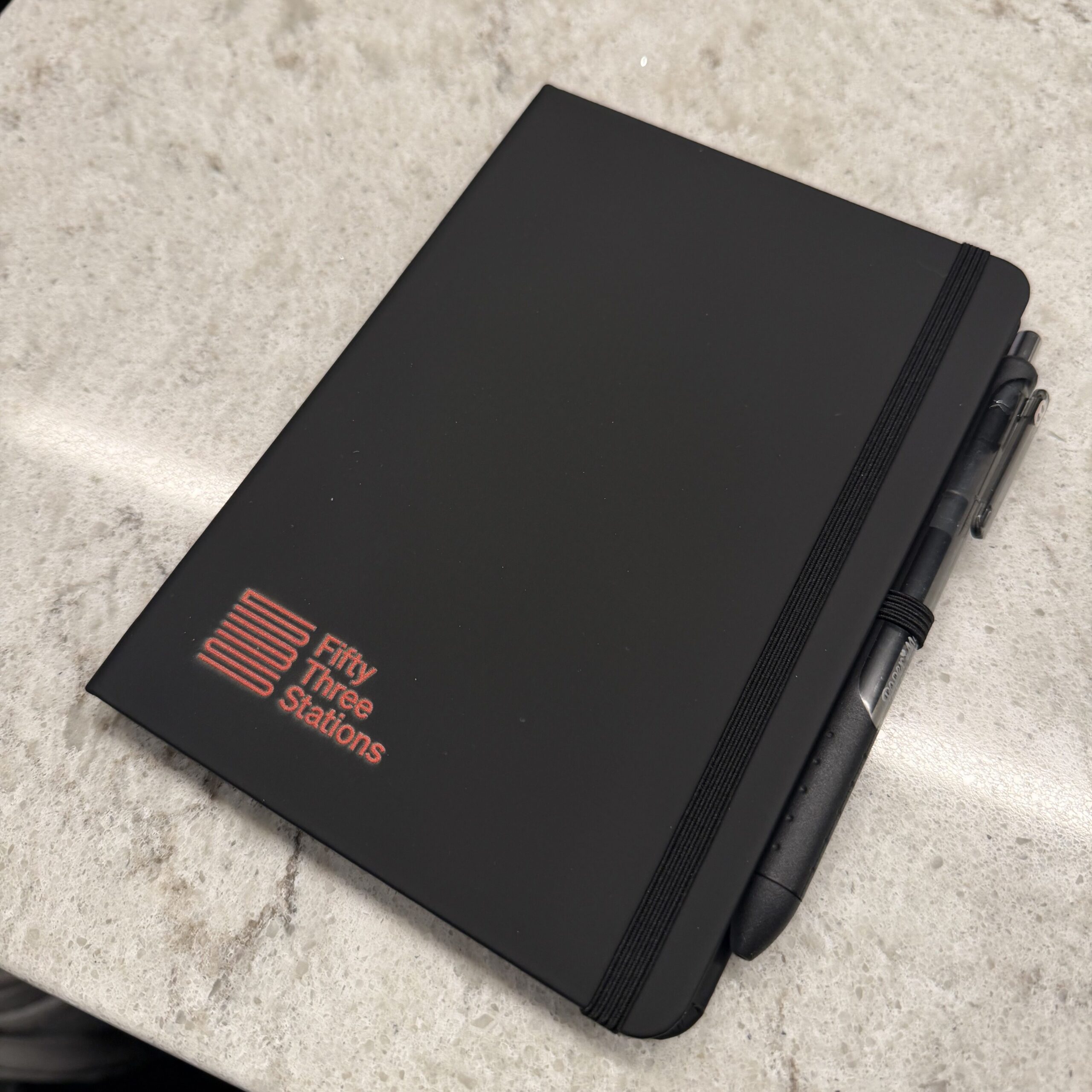 Black notebook with 53 Stations logo. 